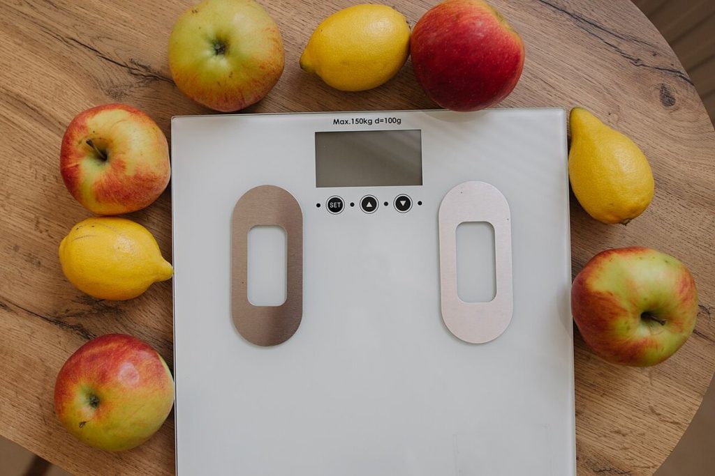 Fresh fruit arranged around a weighing scale on a table