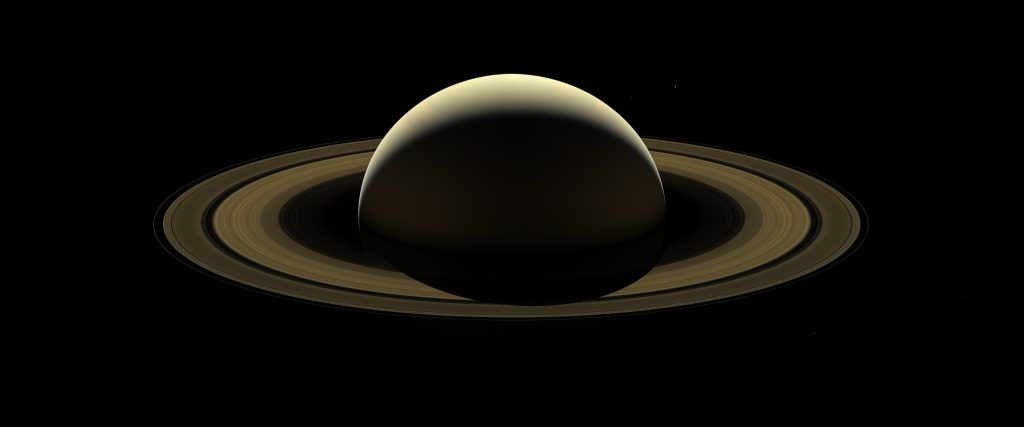 Saturn surrounded by many small moons in deep space